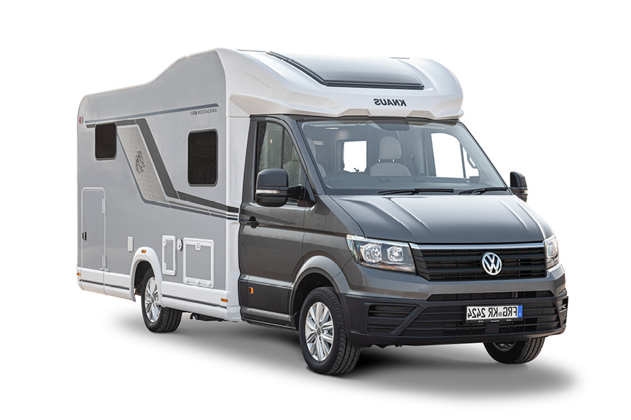 En Knaus Van Wave VW Vansation 640 MEG 2024 autocamper, set fra siden. Billedet viser autocamperens stilfulde og moderne design med en hvid og grå farvekombination. Køretøjet er udstyret med store vinduer og avancerede funktioner, hvilket gør den ideel til komfortabel og fleksible rejser.