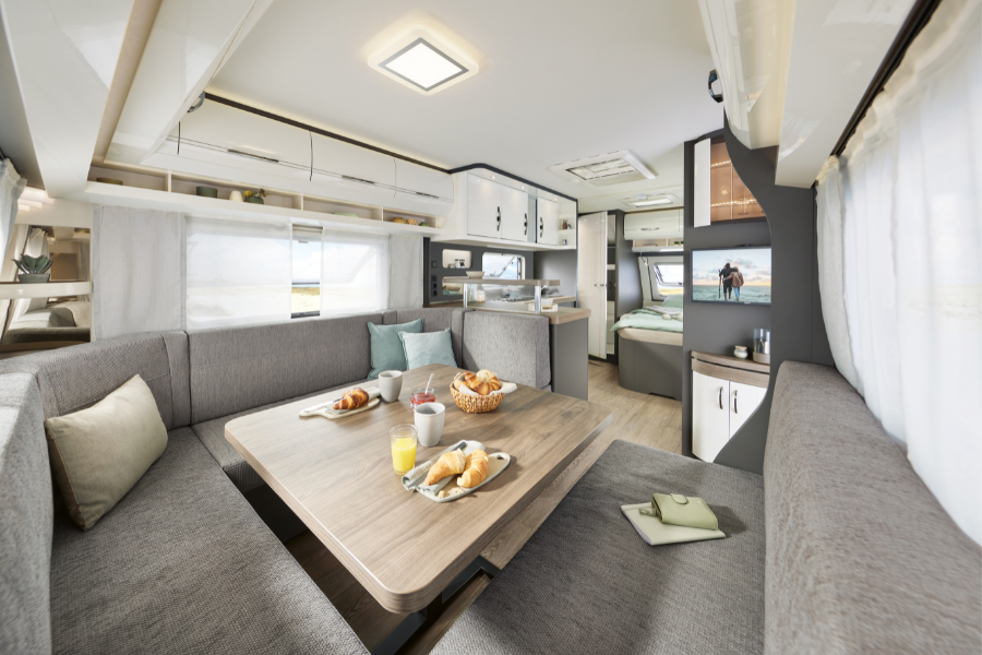 Indvendigt billede af Hobby campingvogn med lys opholdsafdeling, stor siddegruppe, spisebord og komfortabel indretning.